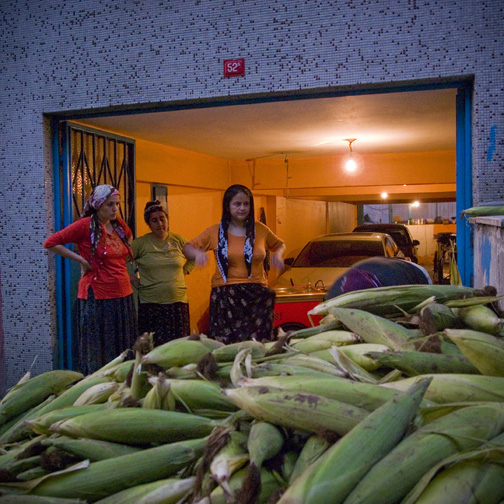 A group of Istanbul women getting ready to shuck a pile of corn for sale in a street cart